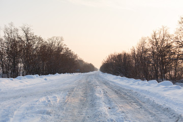 Fototapeta na wymiar Winter poorly cleared road. Road in the countryside strewn with snow. Winter landscape with snowdrifts