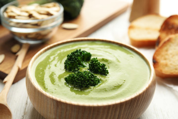 Delicious broccoli cream soup served on white wooden table, closeup