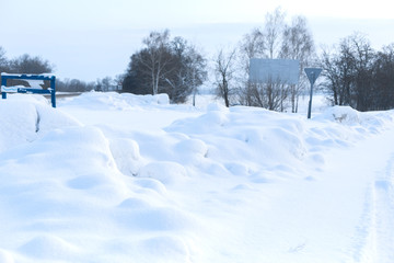 Obraz premium Winter poorly cleared road. Road in the countryside strewn with snow. Winter landscape with snowdrifts