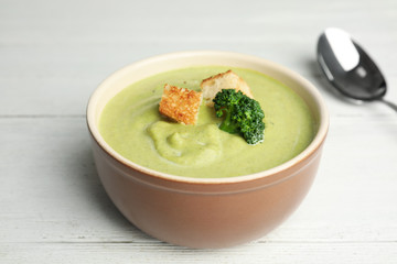 Delicious broccoli cream soup with croutons served on white wooden table