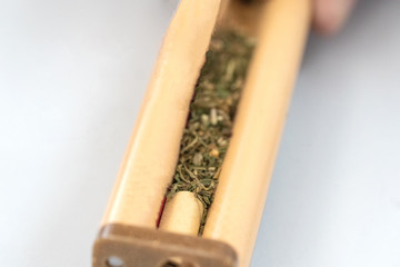 Hands making Marijuana joint from cigarette rolling machine, paper.