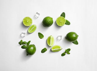 Flat lay composition with fresh juicy limes, mint and ice cubes on white background