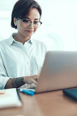 Smiling lady is working on laptop in office