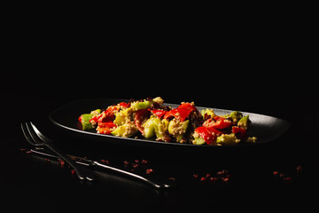 Raw paleo quinoa kale salad in a black plate on the dark background, with copy-paste space. Healthy, vegan, vegetarian and diet eating food.