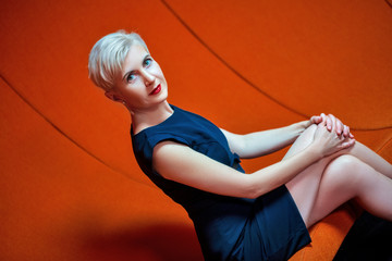business portrait of a middle-aged woman in a blue dress sitting on a red sofa