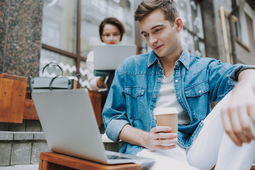 Young man is looking on laptop screen outdoors