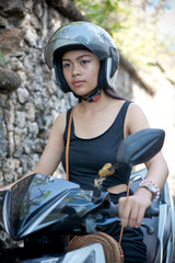 Asian girl; in a black dress on a scooter. Beautiful Balinese women lifestyle portrait