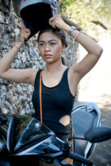 Fototapeta na wymiar Asian girl; in a black dress on a scooter. Beautiful Balinese women lifestyle portrait
