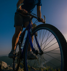 Fototapeta na wymiar Silhouette of a mountain biker riding his mountain sportbike on top of a cliff ( hill).