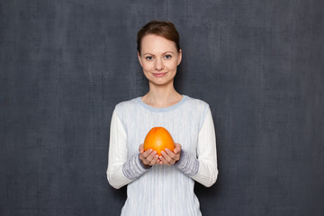 Portrait of happy young woman smiling and holding ripe grapefruit