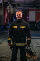 Portrait of young fireman standing inside the fire station.