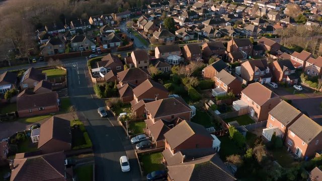 Aerial footage panning down over a housing estate next to a large field during a low sun and a golden sunrise in Hornsea, East Yorkshire, UK