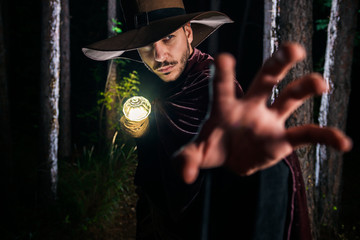 Wizard man in dark woods with lighting stick