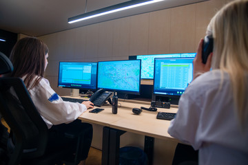 Female security guards working on computers while sitting in the main control room