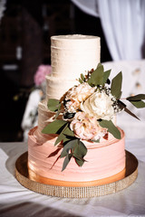 Beautiful four tiered wedding cake decorated with a flowers, outdoors near the festive arch, in the...