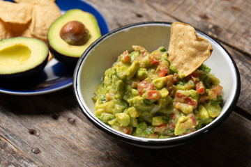 Mexican guacamole with tomato on wooden background - obrazy, fototapety, plakaty