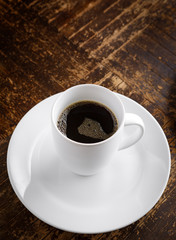 Fresh black coffee in a white mug on a rustic wooden table