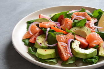 Mediterranean Avocado Salmon Salad with spinach, cherry tomatoes, avocado and red onion dressing. Concept for a tasty and healthy meal. Vegan food