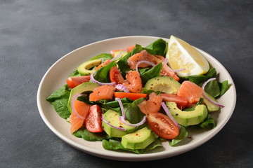 Mediterranean Avocado Salmon Salad with spinach, cherry tomatoes, avocado and red onion dressing. Concept for a tasty and healthy meal. Vegan food