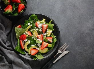 Summer Strawberry Salad with spinach, feta cheese, avocado, balsamic vinegar and olive oil in a plate. Vegan food. Healthy food concept