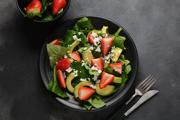 Summer Strawberry Salad with spinach, feta cheese, avocado, balsamic vinegar and olive oil in a plate. Vegan food. Healthy food concept