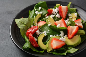 Summer Strawberry Salad with spinach, feta cheese, avocado, balsamic vinegar and olive oil in a plate. Vegan food. Healthy food concept