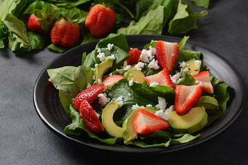 Summer Strawberry Salad with spinach, feta cheese, avocado, balsamic vinegar and olive oil in a plate. Vegan food. Healthy food concept