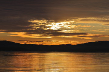 Sunrise in partly cloudy morning over the calm sea. Dawn near the shore of the Sea of Japan.