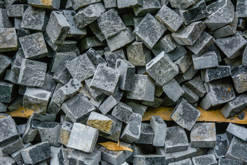 Pile of black natural stone cubes, outdoor pavement tiles. Broken road tiles