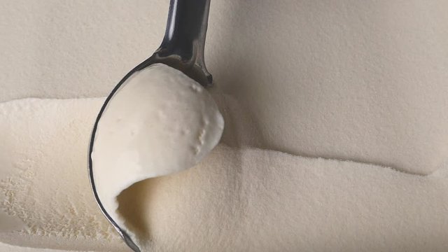Slow motion of scooping Vanilla flavored ice cream out from container with a spoon. Food concept, Blank for design.