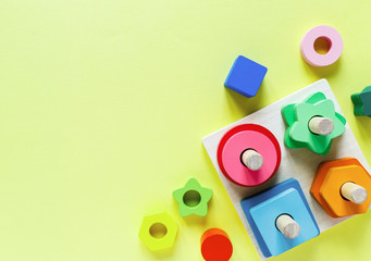 Fototapeta premium Wooden kids toys on colourful paper. Educational toys blocks. Toys for kindergarten, preschool or daycare. Copy space for text. Top view 