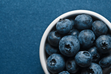 Blueberry bowl on blue background. Color of the year 2020 classic blue trend concept