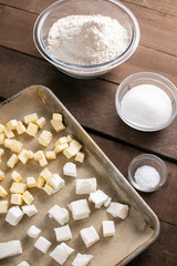 Overhead view on a sheet tray of butter, beside bowls of baking ingredients