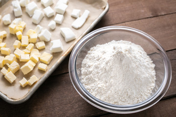 Bowl of flour beside a baking sheet of butter and shortening
