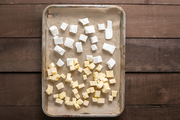Vegetable shortening and butter cubes on a baking sheet, on a wood counter