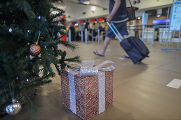 Christmas give, tree decoration with defocused a traveller dragging pull along bag in hurry action to catching flight, and fly home to see a families during long weekend holiday season       