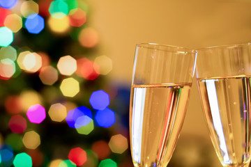 Blurred christmas tree and two glasses with sparkling wine champagne