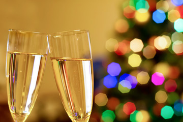Blurred christmas tree and two glasses with sparkling wine champagne. New Year concept