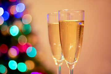 Blurred christmas tree and two glasses with sparkling wine champagne. New Year concept