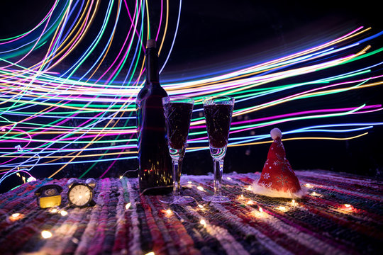 Red wine in crystal glass with bottle on colorful carpet with creative New Year artwork decorations. Copy space