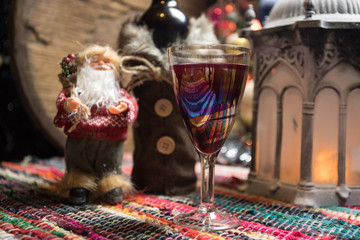 Red wine in crystal glass with bottle on colorful carpet with creative New Year artwork decorations. Copy space