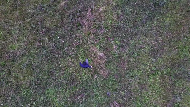 Man goes through field of the grass, shoot from drone - (4K)