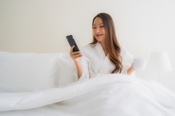 Portrait beautiful young asian women with coffee cup and mobile phone on bed