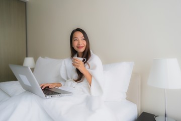 Portrait beautiful young asian women with coffee cup and computer laptop on bed