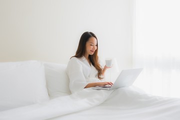 Portrait beautiful young asian women with coffee cup and computer laptop on bed