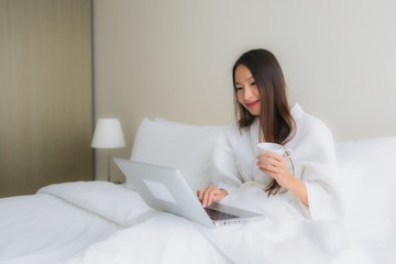 Portrait beautiful young asian women with coffee cup and computer laptop on bed