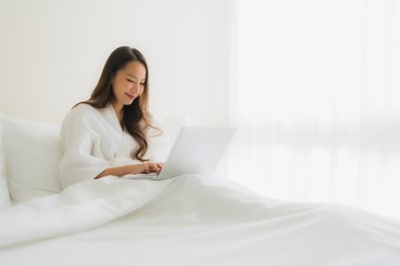 Portrait beautiful young asian women with coffee cup and computer laptop on bed