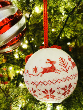 Closeup of round knitted reindeer and snowflakes pattern Christmas Ornament decoration on Christmas tree with lighting