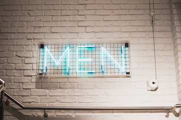 neon sign on white brick wall saying men. Sign in shop for men section. background picture