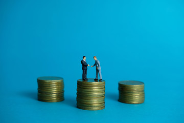 Miniature business concept - two businessman make an handshake for partnership agreement handshake with coin stack